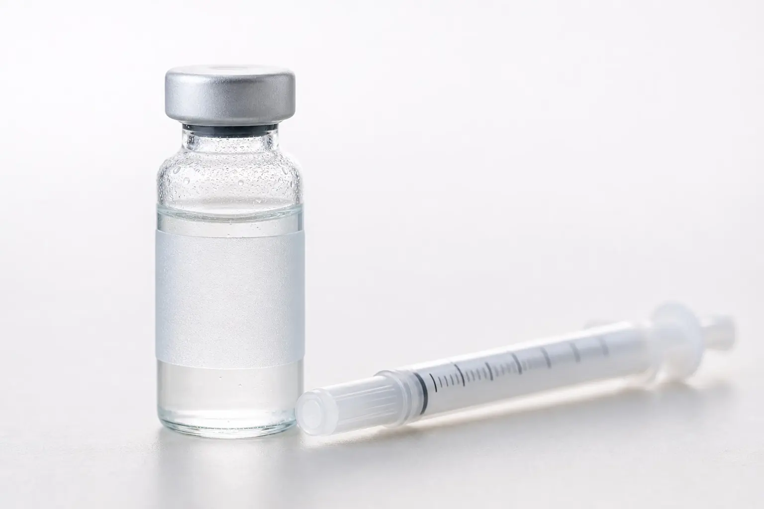 A clear multi-dose vial beside a capped insulin syringe