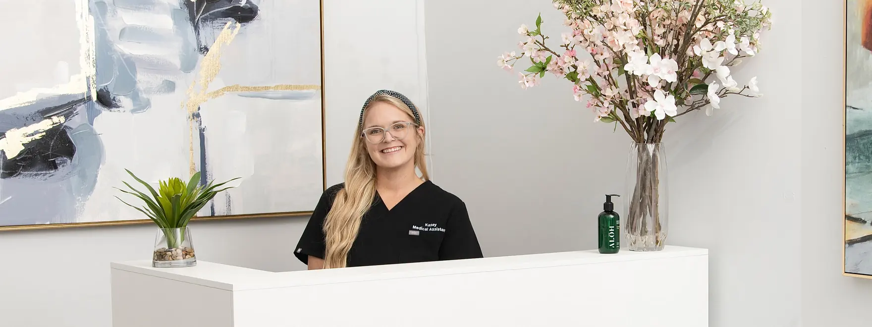 A medical assistant smiling behind the front desk in the Healing Advanced Solutions office in Jacksonville, FL